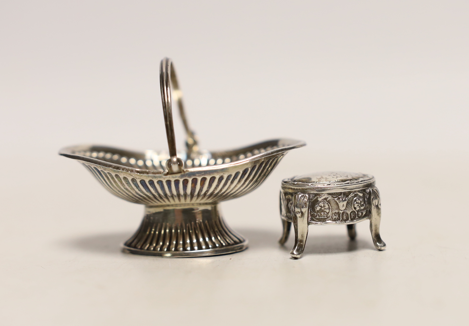 An Edwardian miniature silver model of a basket, by Levi & Salaman, Birmingham, 1907, 56mm, together with a miniature silver model of a table, import marks for London, 1901.